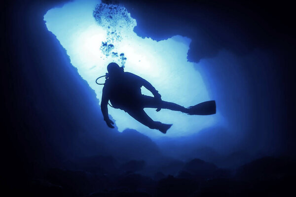 Силуэт аквалангиста в подводной пещере