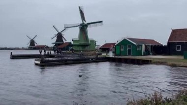 Hollanda 'da nehir kıyısında eski yel değirmenleri. Geleneksel yel değirmeni Hollanda 'daki nehir kanalına yansıdı. Zaanse Schans 'da petrol fabrikası.