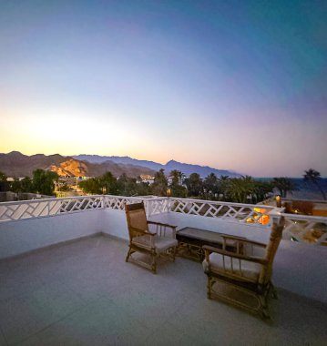 Kuzey Sina, Mısır 'da, Dahab şehrindeki bir binanın çatısında gün doğumunda huzurlu bir şekilde oturmak..