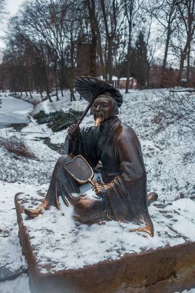 Bronze sculpture of Chinese with umbrella near the Chinese Bridge in the park. Park Oleksandriya in Bila Tserkva, Ukraine.