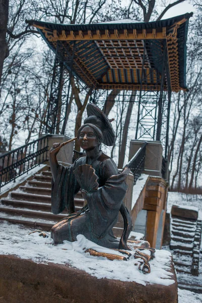 Statue of chinese lady holding an umbrella and a fan in the park of Alexandria in Bila Tserkva, Ukraine.