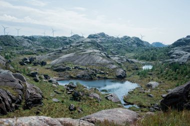 Arka planda yel değirmenleri olan kaya oluşumları, Trollpikken, Norveç, Avrupa