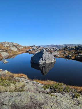 Dağları, mavi gökyüzünü ve nehri olan güzel bir manzara.