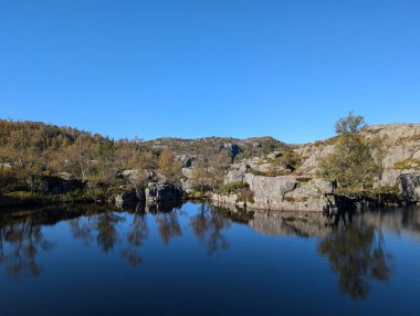 Dağları, mavi gökyüzünü ve nehri olan güzel bir manzara.