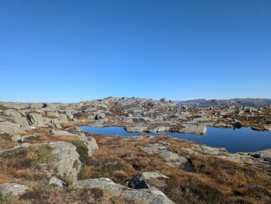 Dağları, mavi gökyüzünü ve nehri olan güzel bir manzara.