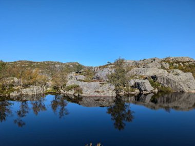 Dağları, mavi gökyüzünü ve nehri olan güzel bir manzara.
