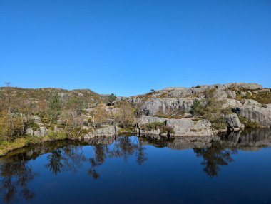 Dağları, mavi gökyüzünü ve nehri olan güzel bir manzara.