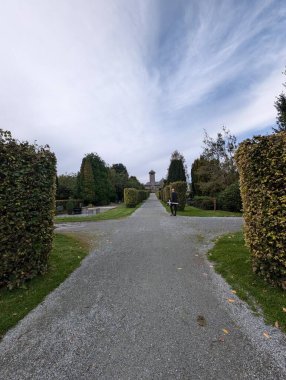 Mezarlıkta elinde beyaz bir haçla yürüyen bir adamın dikiz görüntüsü.