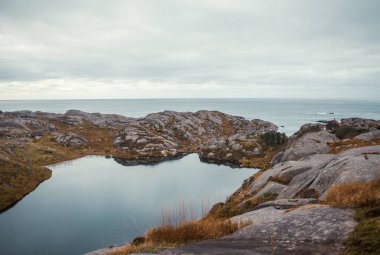 Bulutlu bir günde gölün kayalık kıyısı ve göl.