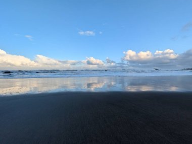 Deniz kıyısının güzel manzarası, suya yansıyan bulutlar.