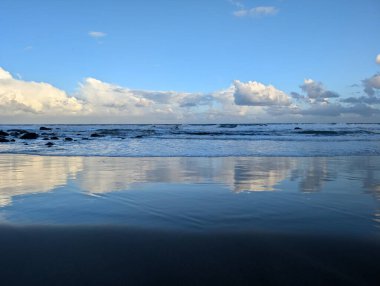Deniz kıyısının güzel manzarası, suya yansıyan bulutlar.