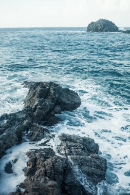 Dalgalar okyanus kıyısındaki kayalara çarpıyor.