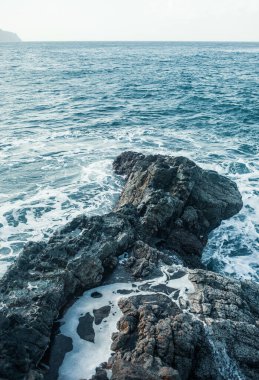 Dalgalar okyanus kıyısındaki kayalara çarpıyor.