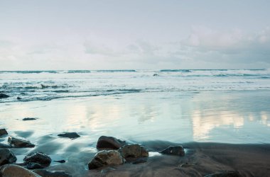 Deniz kıyısının güzel manzarası, suya yansıyan bulutlar.