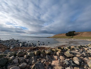 Rocks rest quietly near stormy waves