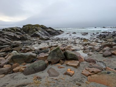 Rocks rest quietly near stormy waves