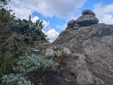 Kayalar ve bitkilerle dolu güzel bir dağ manzarası mavi gökyüzüne karşı bulutlar