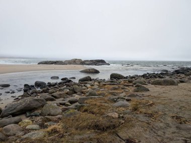 Calm sea meets rocks beneath clouds