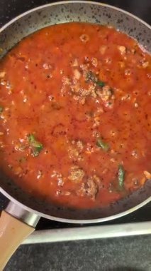 Domates sosunu kızartma tavasında haşlamak için otlar ve etle. 