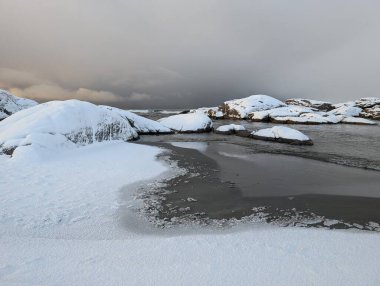Sahilde, kışın karlı büyük kayalar. 