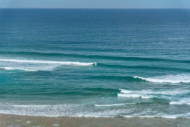 Port Campbell Victoria Avustralya 'da büyük bir okyanusta yalnız sörfçü.