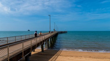 Palm Cove, Queensland - Avustralya - 05-28-2025 Palm Cove Jetty. İskeleden sahilin harika manzarası. Etrafta bir sürü insan dolaşıyor ya da balık tutuyor..