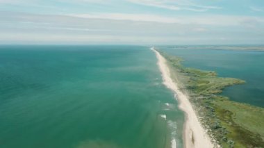 Kumlu bir okyanus sahilindeki dalgaların havadan görünüşü. Yaklaşan dalgalar tekrar tekrar kumlu tropikal kıyılara çarpıyor. Kumlu ve dalgalı plajın hava aracı görüntüsü.