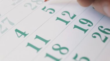A businessman marking important dates on his calendar with a red pencil. Planning important business meetings and events. Close-up 4k photography.