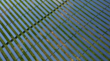 Güneş enerjisiyle çalışan sıra sıra güneş panelleri olan bir güneş çiftliğinin havadan görünüşü. Güneş panelleri büyük bir alana yerleştirilmiştir. Çevre koruma. Yenilenebilir alternatif enerji kaynakları.