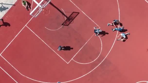 公共の屋外裁判所でバスケットボールをするティーンエイリアンダウンビュー 大学の遊び場でバスケットボールにボールを投げる若者たち — ストック動画