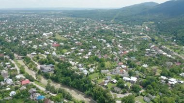Yeşil dağlarla çevrili büyük bir köyün insansız hava aracı görüntüsü. Dağ vadisindeki bir kasabanın insansız hava aracı görüntüsü.