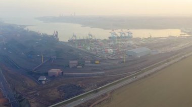 Güneşli bir yaz akşamında kargo bölmesinin havadan görüntüsü. Liman kargo alanı, konteynırlar, kargolar, vinçler, kamyonlar. Akşam endüstriyel manzara gün batımında.