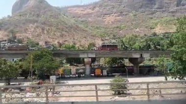 Otoyoldaki arabalar ve kamyonlar ve trenin içinden büyük dağ manzarası.