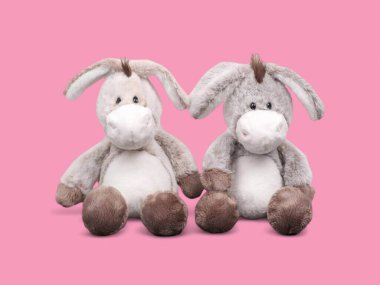 Pembe arka planda iki komik, tapılası, masum eşek yumuşak oyuncak.