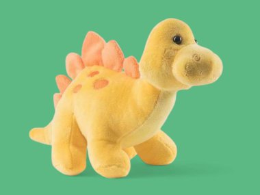 Yeşil arka planda izole edilmiş sarı yumuşak oyuncak dinozor.
