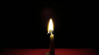 koyu arka plan üzerinde yanan bir mum yakın çekim