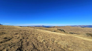 Panoramic view of the Parang Mountains from the top of the Transalpina Road Belvedere on a sunny day. Valcea, Romania clipart