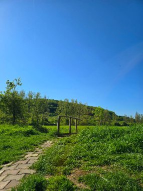 Kırsal ahşap köprü, beton döşeme izleri ve açık mavi bir bahar gününde yeşil çimenler. Cluj, Romanya