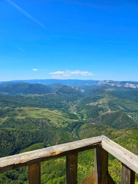 La Balcon - Bedeleu Dağı 'nın tepesindeki ahşap balkon inşaatında duruyor, açık bir yaz gününde dağları ve Aries Vadisi' ni seyrediyor. Salciua, Alba, Romanya