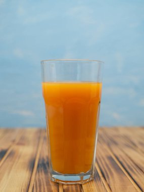 Fresh juice, mix fruits, orange drink on a blue background. Glass with orange cocktail.