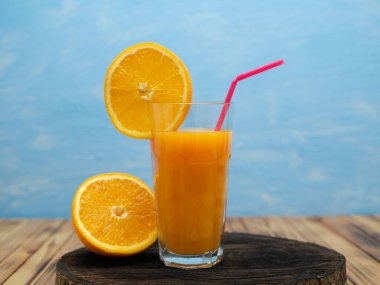 Fresh juice, mix fruits, orange drink on a blue background. Glass with orange cocktail.