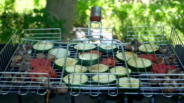 Adam barbeküde kızartılmış sebzeleri çeviriyor. Domates, kabak ve mantar mantarı ızgarada kızartılır. Yakın plan.
