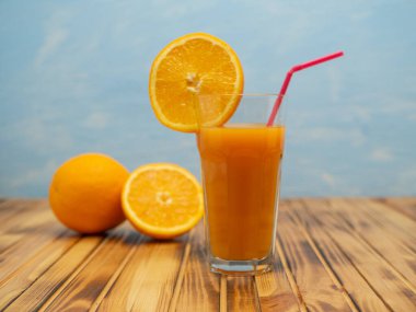 Fresh juice, mix fruits, orange drink on a blue background. Glass with orange cocktail.