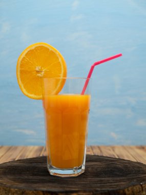 Orange juice in a glass with a slice of orange and an straw.