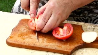 Kadın elleri mutfak bıçağı kullanarak tahta kesme tahtasıyla taze domates kesiyor. Sağlıklı beslenme. Kesilmiş domates..