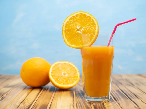 Fresh juice, mix fruits, orange drink on a blue background. Glass with orange cocktail.