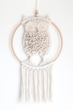 Hand woven white macrame owl in ring hanging on wall clipart