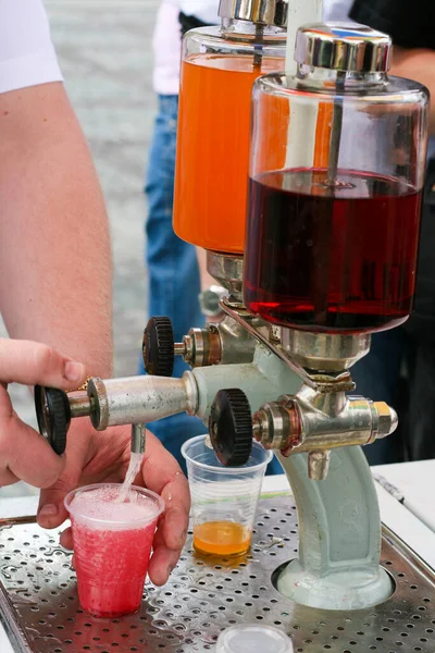Pouring carbonated drink from saturator. Tap and syrup glass tanks of flavoured soda maker drink stand