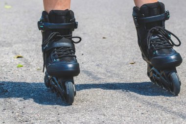 Legs of woman who is learning of inline skating on asphalt road