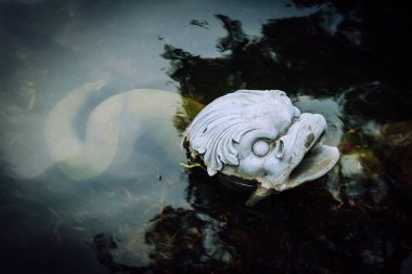 Halka açık park gölünde sudan çıkmış dökme demir canavarın başı.